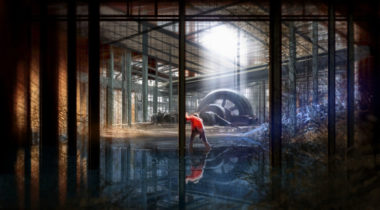 A man bending over in front of an industrial building.